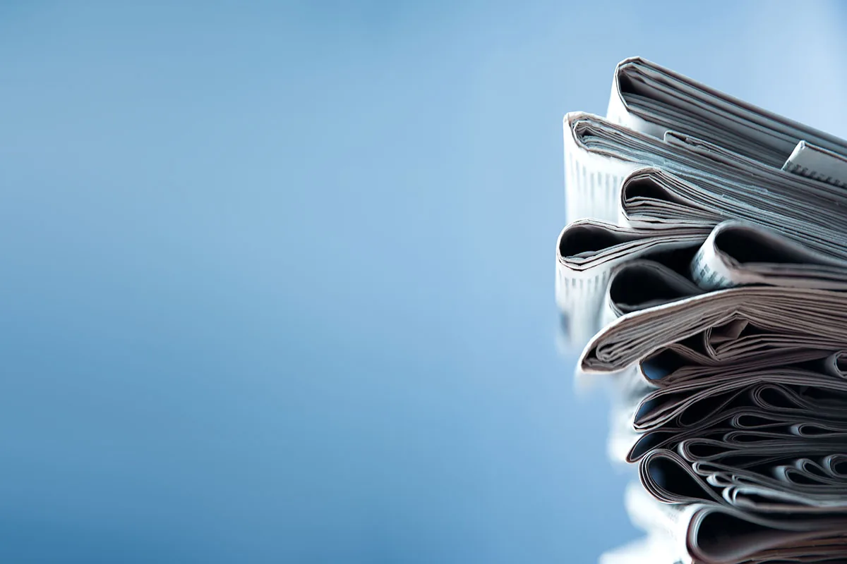 A stack of folded newspapers against a blue background.